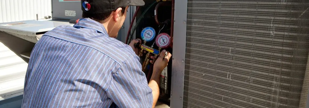 HVAC technician servicing a condenser unit in Dudley